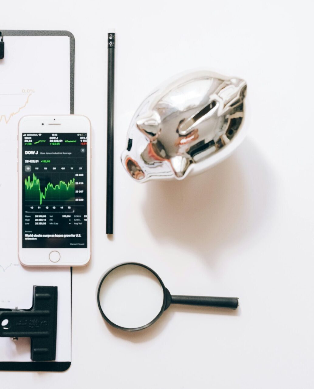 Smartphone mit Börsenkursen, Sparschwein und Lupe als Symbol für unabhängige Vermögensverwaltung